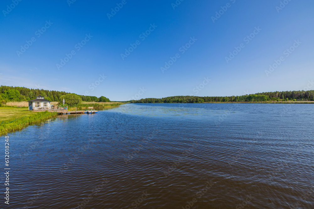 Beautiful view of landscape of nature of lake with pier for parking boat and forest trees on opposite shore. Sweden.