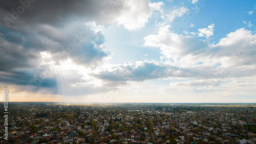 beautiful sky with sunbeams and clouds over the green city