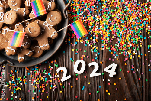 New year background of tray with gingerbread cookie men, rainbow flags and color sprinkles on wooden table