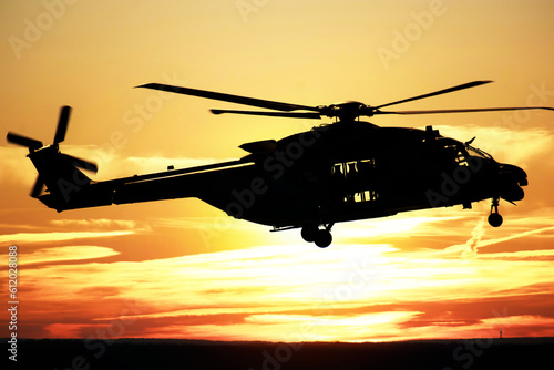 Silhouette of a combat helicopter at sunset in the sky, side view, air transportation