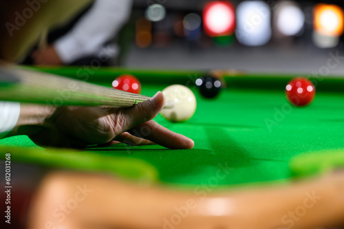 Hand of professional snooker player closeup aiming shot white ball on snooker table.