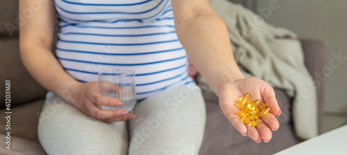 Pregnant woman drinks omega three. Selective focus.