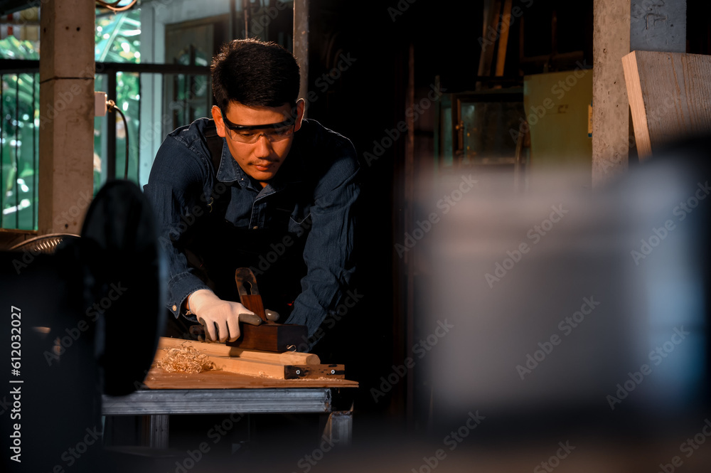 Asian carpenter craftsman making pool cue or snooker cue with a manual hand wood planer in carpentry workplace in an old wooden shed. Handmade craftsman concept.