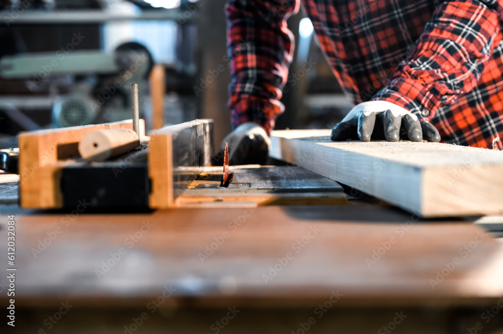 Carpenter working with machine electronic table circular saw for cutting plank wood in the workshop, Carpentry woodwork.