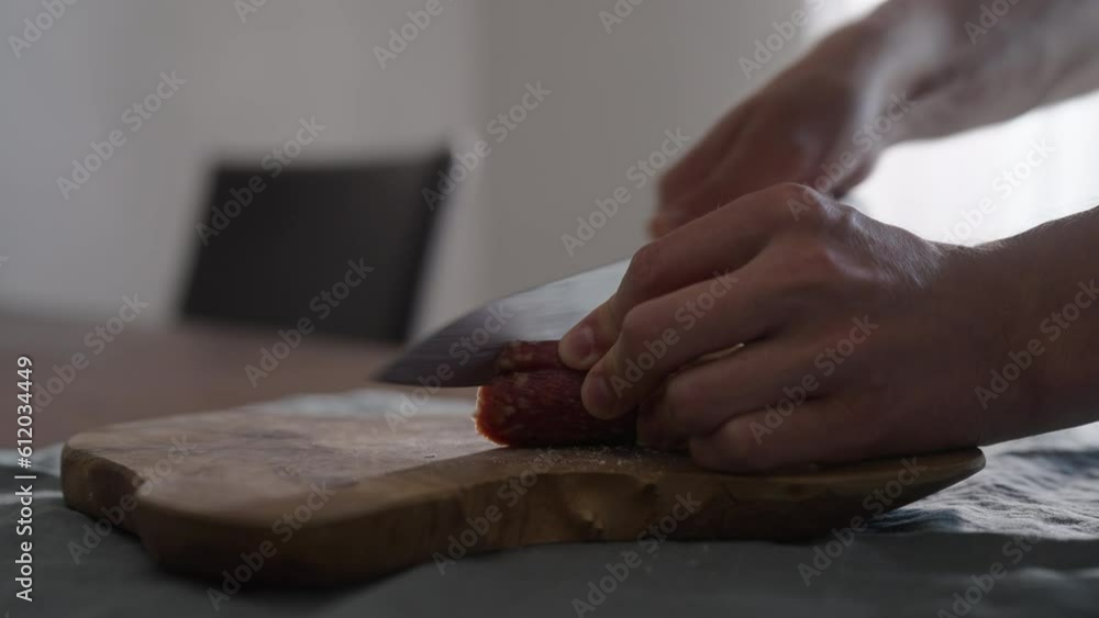 Man slicing mini salami sausage on wood board Man slicing mini salami sausage on wood board
