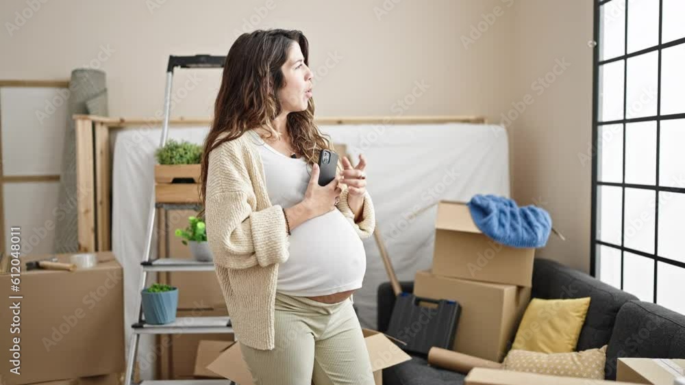 Young pregnant woman using smartphone looking around thinking at new home Young pregnant woman using smartphone looking around thinking at new home