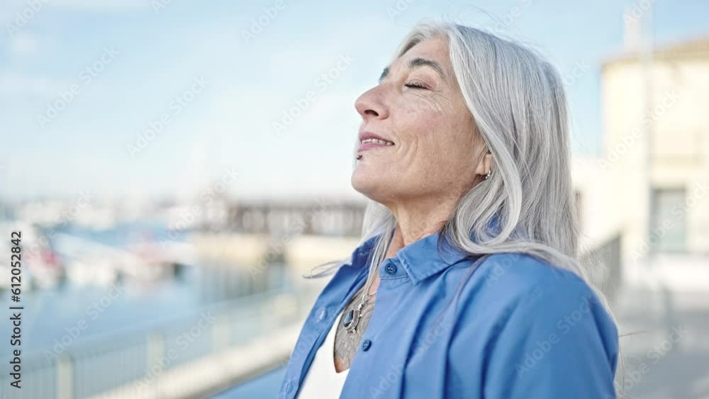 Middle age grey-haired woman smiling confident breathing at seaside Middle age grey-haired woman smiling confident breathing at seaside