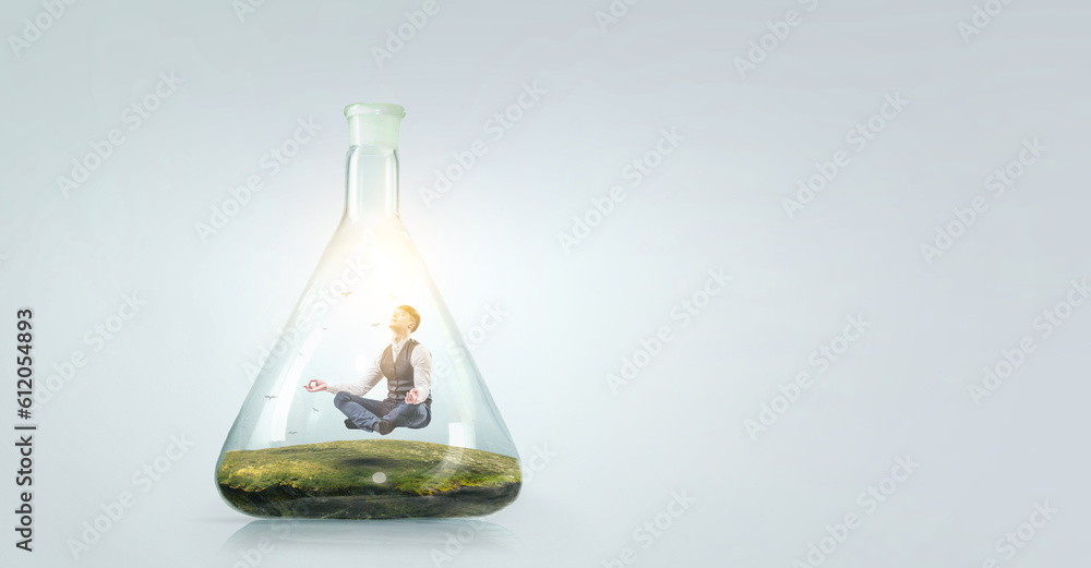 Business man doing yoga in lotus pose inside glass bottle Business man doing yoga in lotus pose inside glass bottle