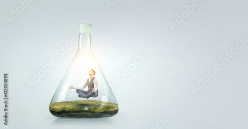 Business man doing yoga in lotus pose inside glass bottle