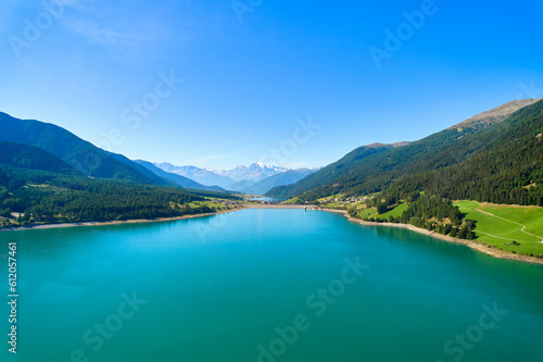 Aerial view of lake (Reschensee). Large reservoir surrounded by mountains at sunny noon. Recreation area for tourists and sportsmen. Italy, Vinschgau, Lake Resia.