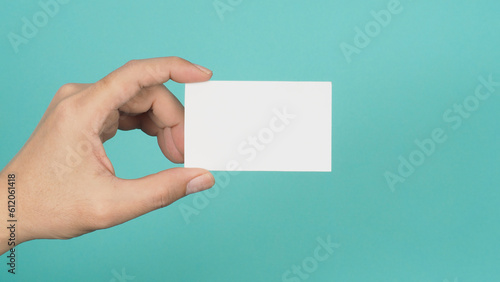 Hand holding white blank card isolated on mint green or Tiffany Blue background.