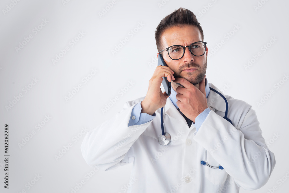 Mid aged male doctor using cellphone and standing at isolated background Mid aged male doctor using cellphone and standing at isolated background