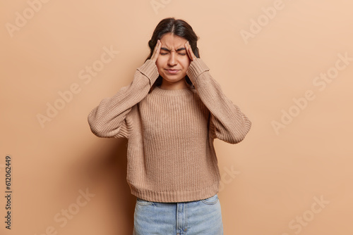 Fotografie Iranian woman holds her temples her eyes closed tightly in attempt to alleviate