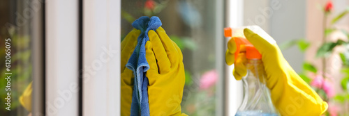 Woman applying detergent spray and rag for cleaning window outside