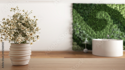 Fototapeta Naklejka Na Ścianę i Meble -  Wooden table top or shelf with pottery vase with daisies, wild flowers, over bathroom with vertical garden in minimal style, modern interior design concept