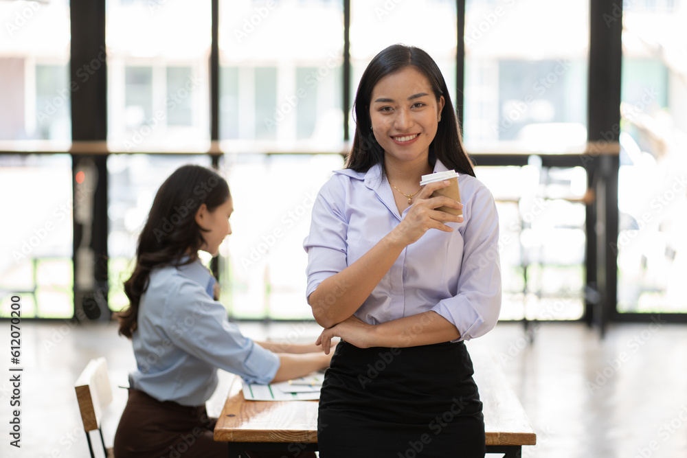 Portrait of a Caucasian pretty business lady smiling to the camera and crossing her hands while standing on the glass building background indoors Portrait of a Caucasian pretty business lady smiling to the camera and crossing her hands while standing on the glass building background indoors