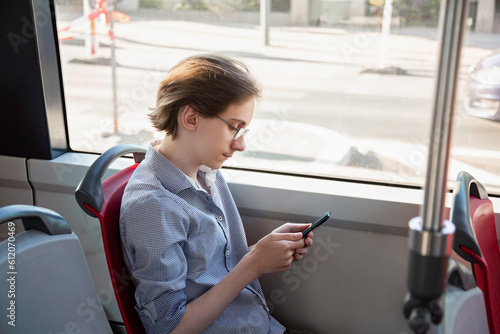 Wallpaper Mural Tennager boy in a tram holding mobile phone in his hand. Guy siting near a window, looks with interest at screen of smartphone, playing mobile games online on smartphone connected to public wifi Torontodigital.ca