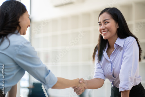 Recruiter shaking hands with a young female candidate after a job interview.