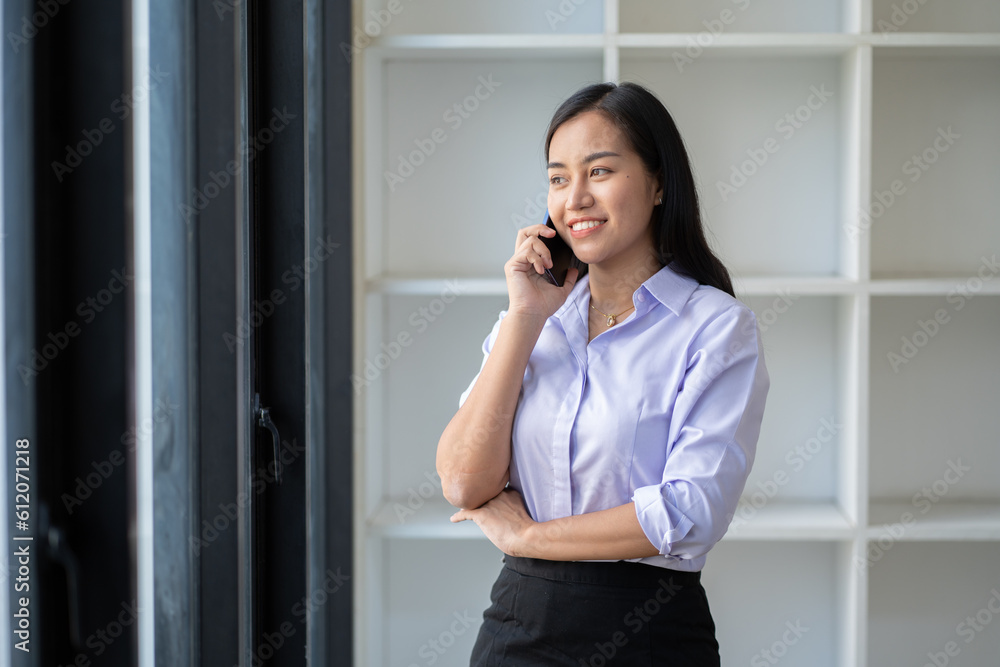 Asian businesswoman playing with mobile phone inside modern office