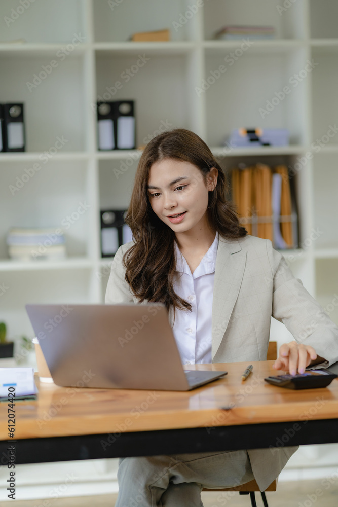 Young female accountant, company worker working with laptop and accounting documents checking financial data or marketing reports working in office