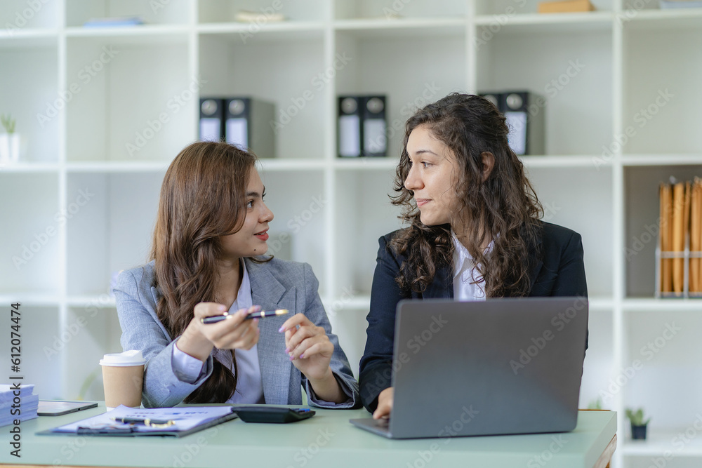 Businesswoman and accountant talking with laptop and tablet Two attractive millennial caucasian businesswoman planning project together at table in office Businesswoman and accountant talking with laptop and tablet Two attractive millennial caucasian businesswoman planning project together at table in office