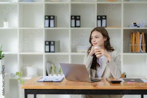 Young female accountant, company worker working with laptop and accounting documents checking financial data or marketing reports working in office