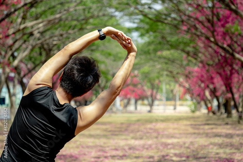 фотографія Asian athlete man with well trained body in black sportswear stretching arms and shoulders overhead