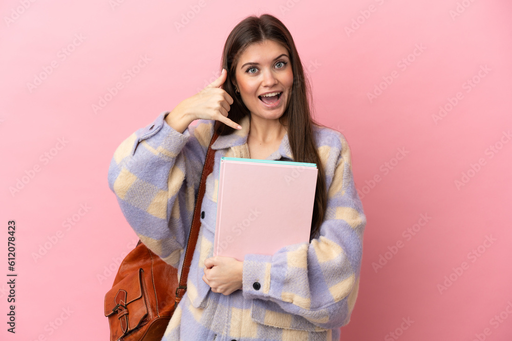 Young student woman isolated on pink background making phone gesture. Call me back sign Young student woman isolated on pink background making phone gesture. Call me back sign