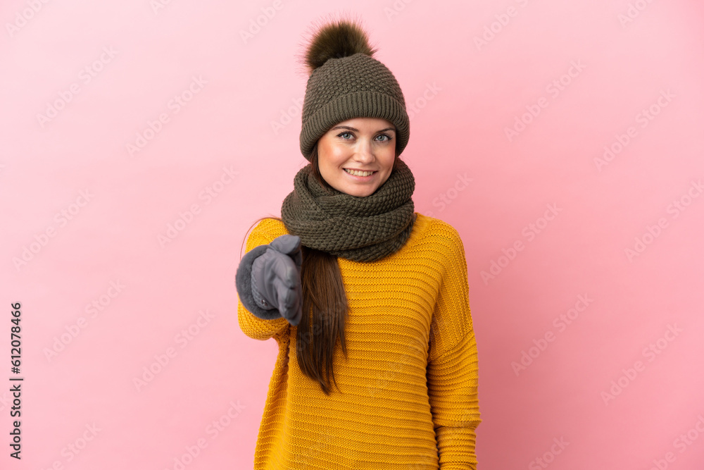 Young caucasian girl with winter hat isolated on pink background shaking hands for closing a good deal Young caucasian girl with winter hat isolated on pink background shaking hands for closing a good deal