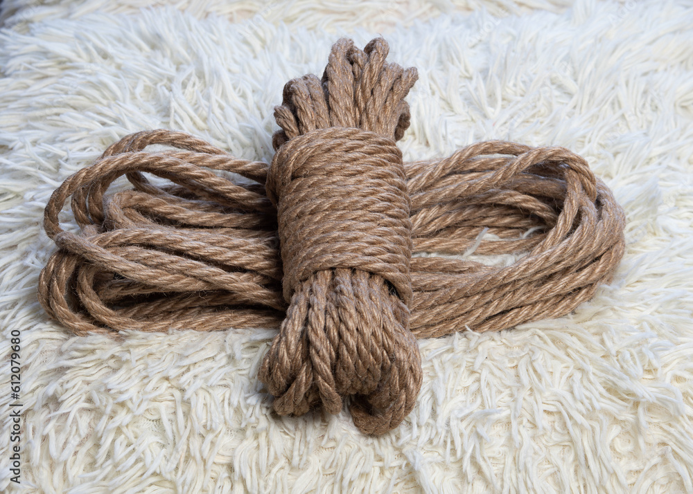 A coil of jute rope for shibari practice on a fleecy white background. Shibari. Concept of BDSM.	