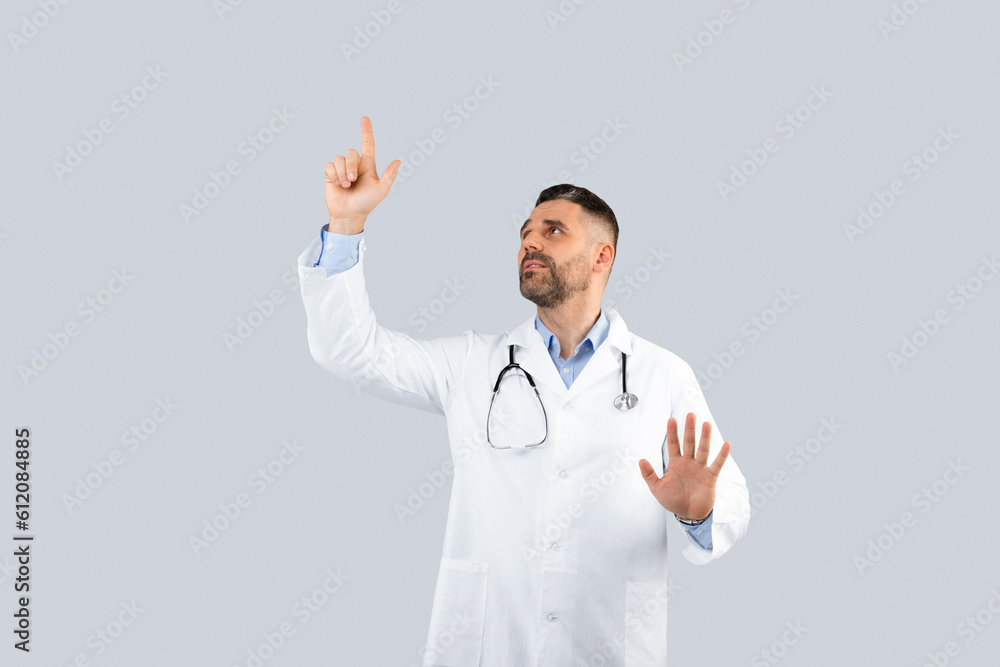 Confident middle aged man therapist in white coat controlling virtual screen with hands on empty space, light background Confident middle aged man therapist in white coat controlling virtual screen with hands on empty space, light background