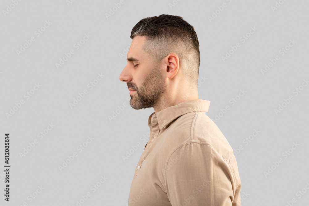 Profile shot of middle aged bearded man in shirt standing with closed eyes over light background, side view, copy space Profile shot of middle aged bearded man in shirt standing with closed eyes over light background, side view, copy space