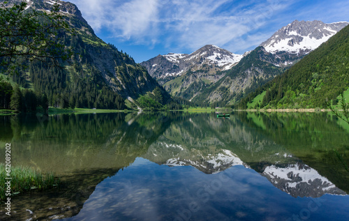 Wandern in Österreich, nahe dem Allgäu: der schöne Bergsee Vilsalpsee in den Tannheimer Bergen in Tirol mit Angler und Boot später Frühling, früher Sommer im Mai
