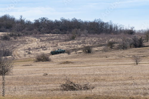 Fototapeta Naklejka Na Ścianę i Meble -  A BTR-80 armored personnel carrier in green camouflage is driving on a barren winter hill
