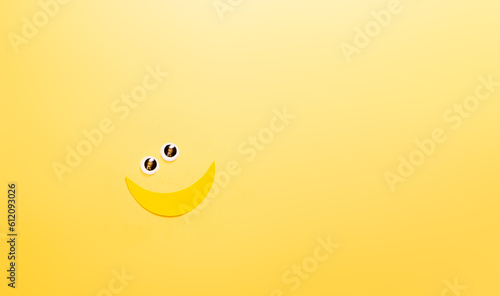 Banner con emoticones de carita sonriente y banana con ojitos. espacio para texto, en fondo amarillo, concepto de dia mas feliz del año, happy yellow day, verano. photo