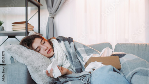 Sick sleeping. Catching cold. Tired woman wrapped in plaid laying couch napping with tissue hand high temperature body ache weakness home interior.