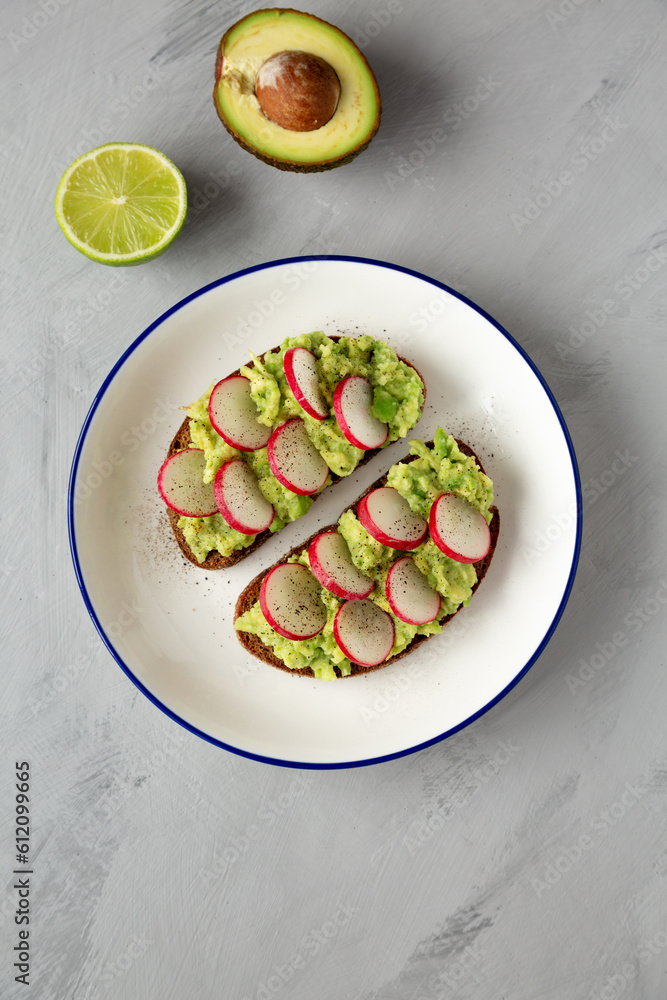Homemade Radish Avocado Toast with Salt and Pepper on a Plate, top view. Close-up. Homemade Radish Avocado Toast with Salt and Pepper on a Plate, top view. Close-up.