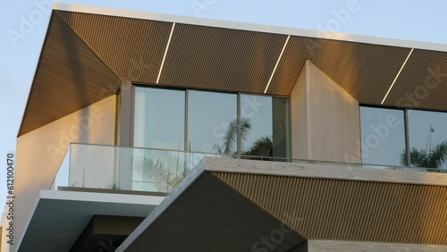 Close up of modern house exterior design in hi-tech style with usage of fluted wooden panels and glass. Residential building of two floors