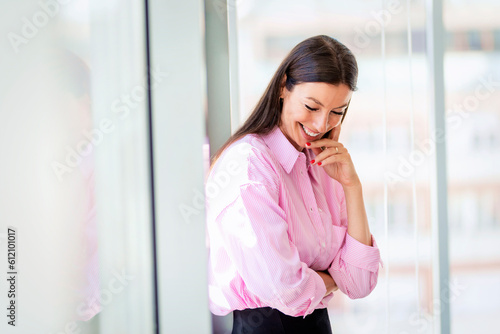 Brunette haired businesswoman standing with arms crossed in a glass office