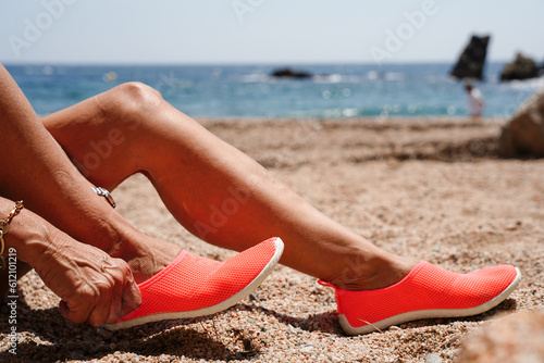 Two legs with an orange beach flip flops in the beach sand on summer holidays.