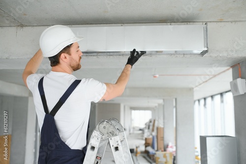 Industrial Theme. Warehouse Heating and Cooling System Installation by Professional Caucasian Technician. Commercial Building Ventilation Rectangle Canals. Air Distribution. photo