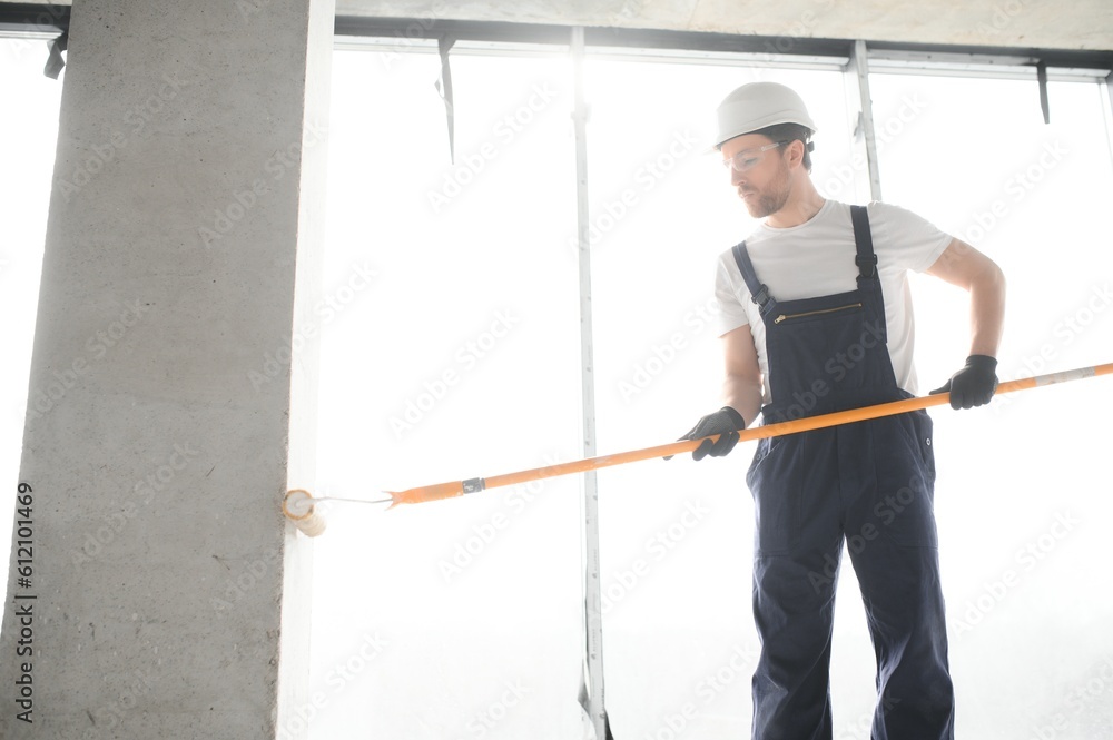 Worker renewing apartment on wall background.