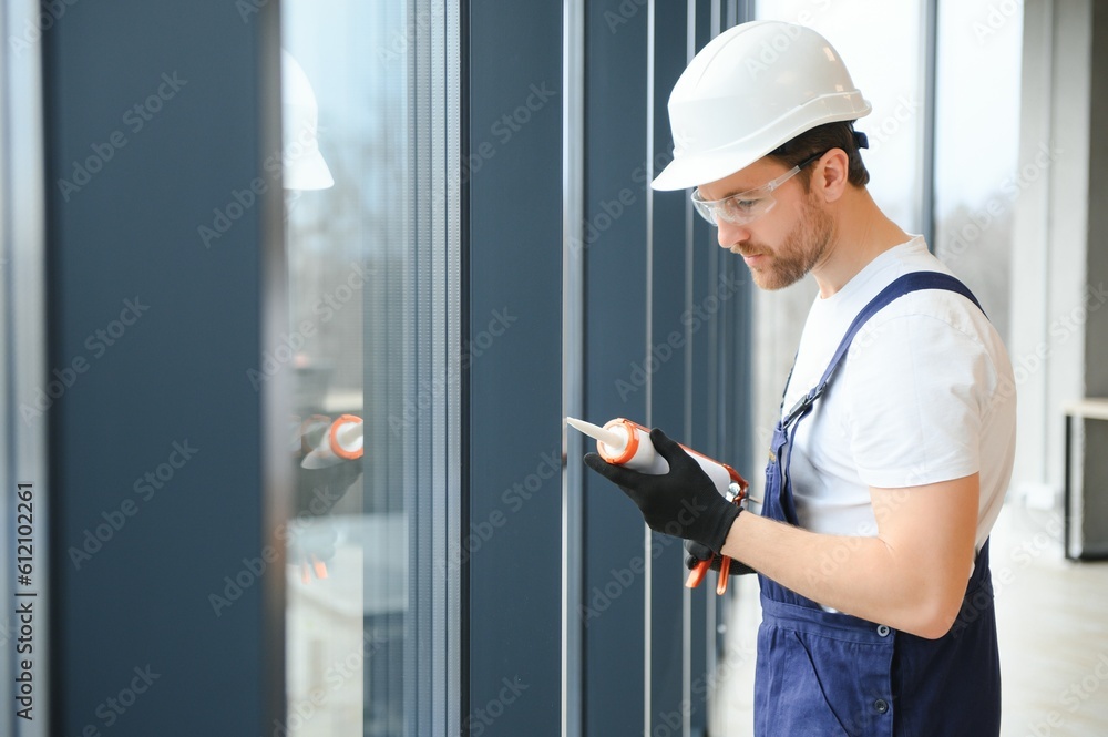 handsome young man installing bay window in new house construction site. handsome young man installing bay window in new house construction site.