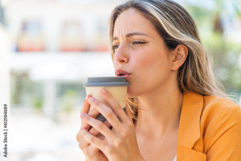 Young pretty woman at outdoors holding a take away coffee Young pretty woman at outdoors holding a take away coffee