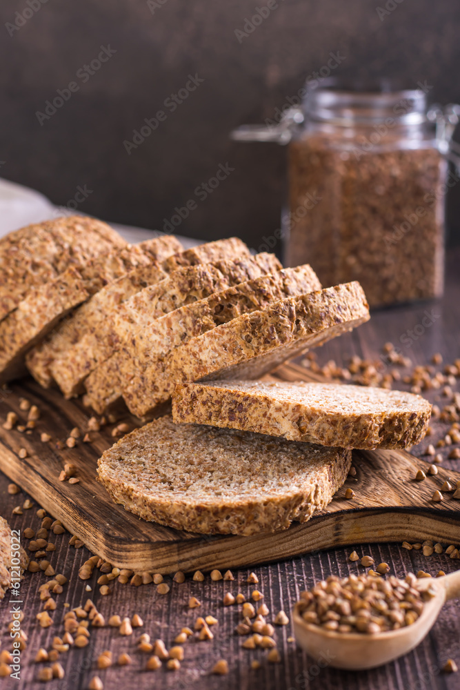Sliced buckwheat bread on a cutting board and cereals on the table vertical view Sliced buckwheat bread on a cutting board and cereals on the table vertical view