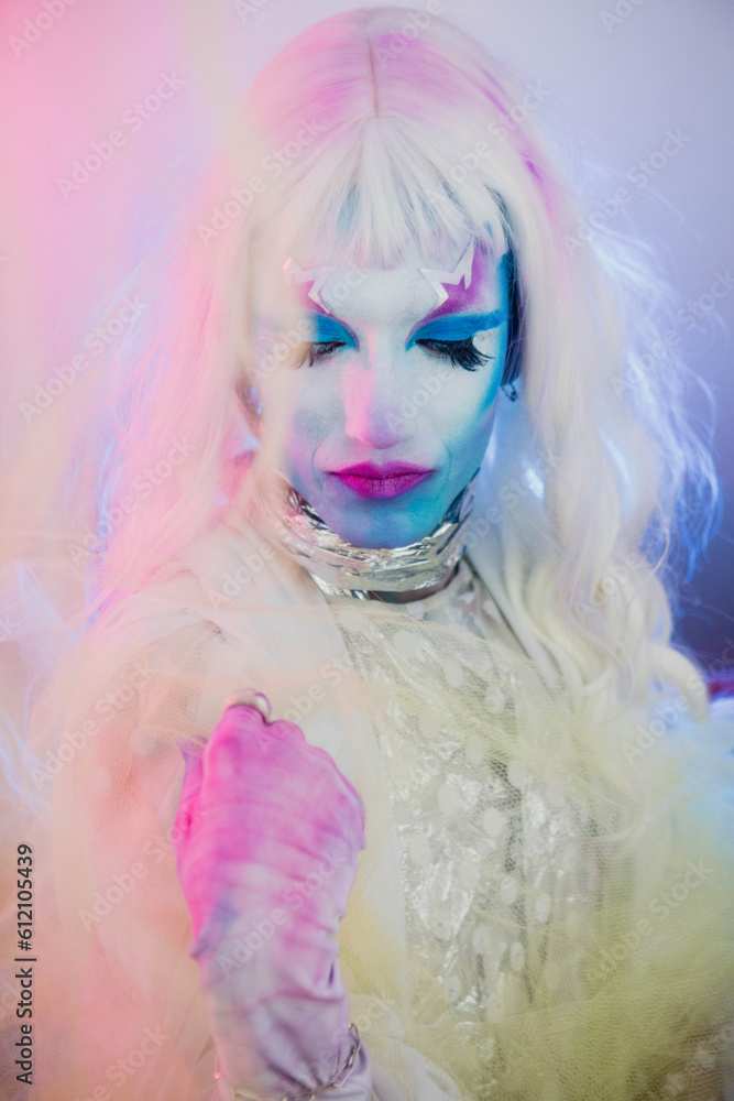 Fototapeta premium Close up on Drag queen trans person man in pink and blue light star makeup and white wig hair 