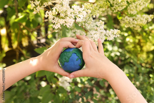 Fototapeta Naklejka Na Ścianę i Meble -  plasticine planet Earth in children's hands on a background of flowers. day earth, save environment concept
