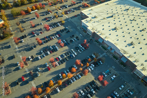 View from above of american grocery store with many parked cars on parking lot with lines and markings for parking places and directions. Place for vehicles in front of a strip mall center