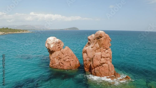 Aerial view of red cliffs in the sea at sunset in summer. Top drone view of rocks, transparent blue water, empty sandy beach in Sardinia island, Italy. Tropical. Exotic place. Nature