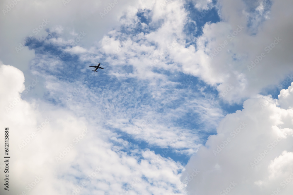 Commercial airplane flying through white and gray clouds and a blue sky above Florida Commercial airplane flying through white and gray clouds and a blue sky above Florida